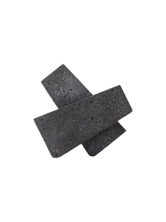 The Converge Bookends interlocked as an abstract black lava-stone sculpture on a white background.