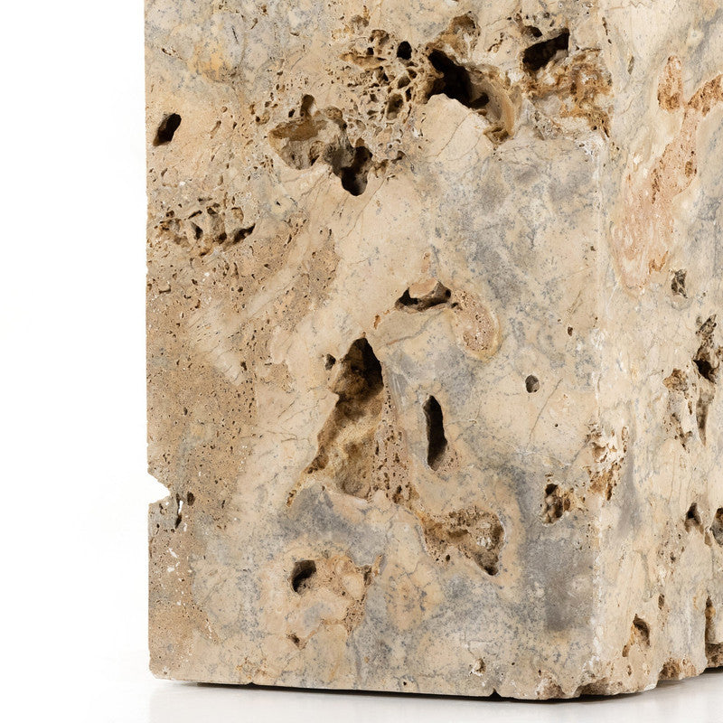 The Palu Accent Table in a second editorial interior setting, emphasizing its monolithic form, natural cavities, and mineral-rich Romano Fosse travertine.