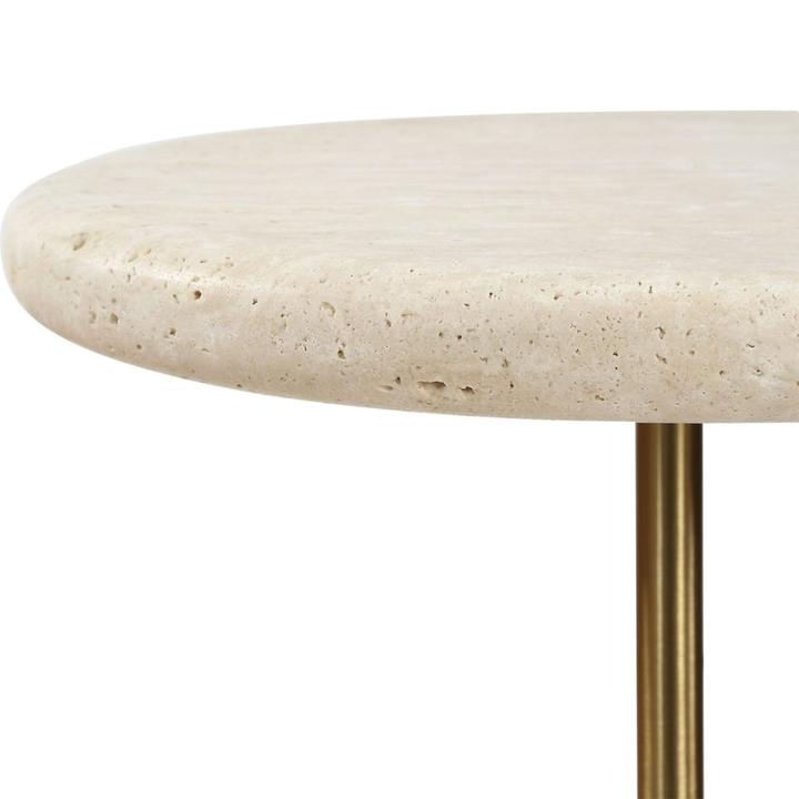 Close detail of the rounded travertine tabletop and brushed-brass-finished support on The Rémi Drink Table.