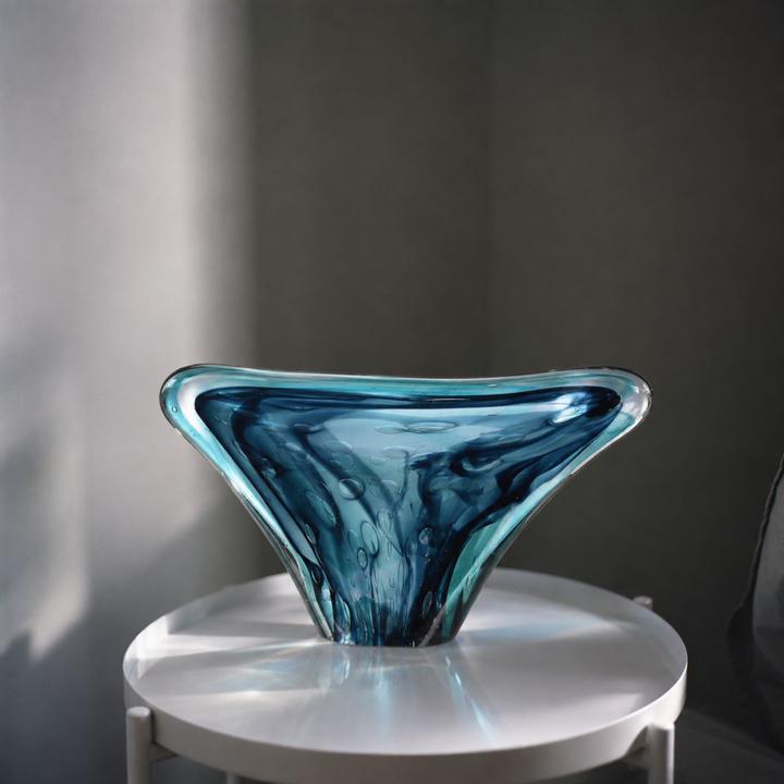 Océane Glass Sculpture displayed on a round reflective table against a dark gray wall.