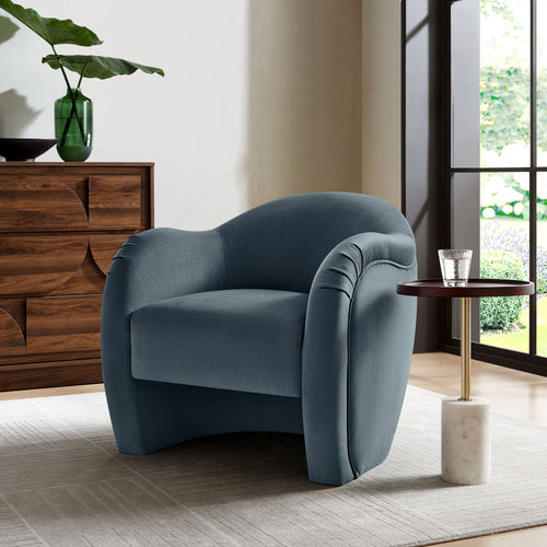 Storm-blue velvet curved armchair placed beside a marble-top side table in a modern living room