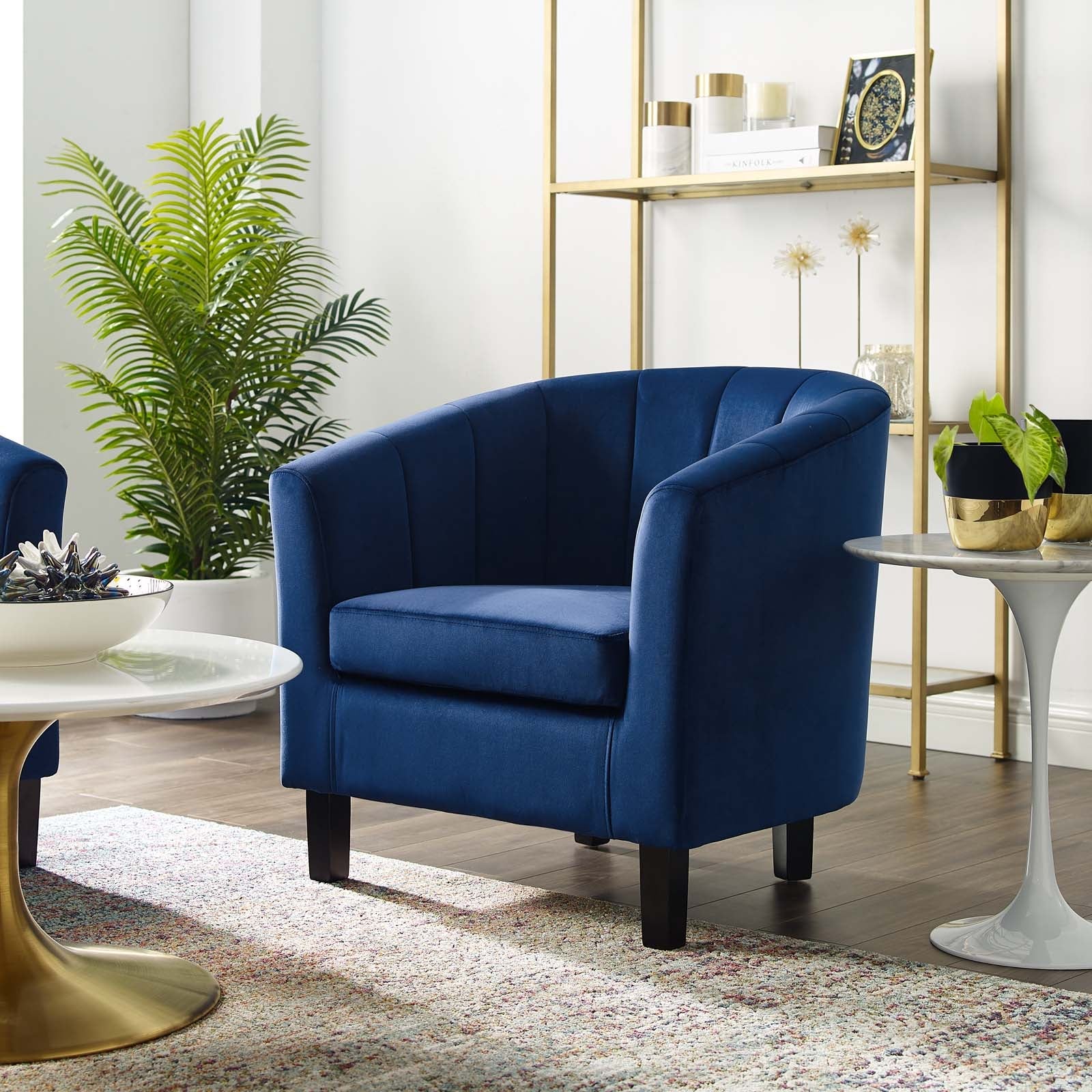 Storm-blue velvet curved armchair placed beside a marble-top side table in a modern living room