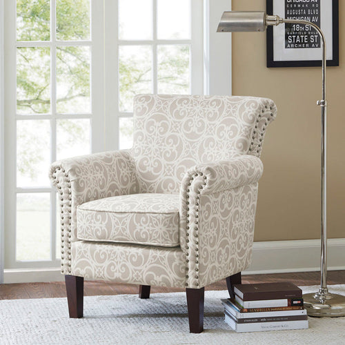 Beige patterned club chair styled beside a reading lamp and stacked books