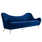 Navy blue velvet sofa with channel-tufted curved back and tapered brushed gold legs, three-quarter view