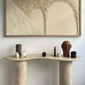 The Céleste Console styled in a hallway beneath framed art, holding a candle and small sculptural objects.