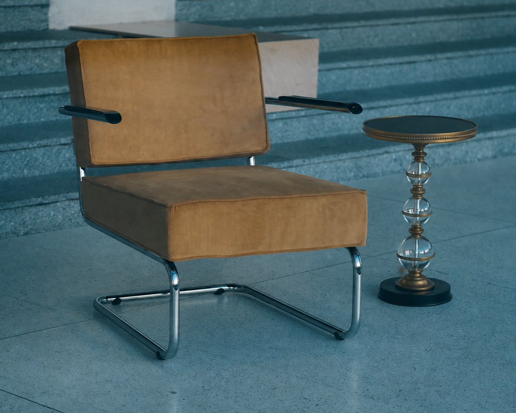 Béatrice Pedestal Side Table placed beside a mustard upholstered cantilever lounge chair in a cool-toned architectural interior.