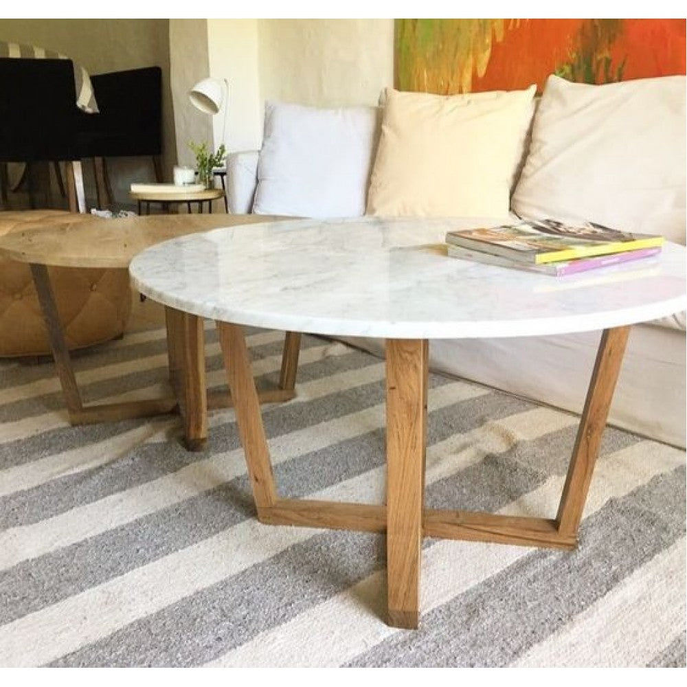 Round marble coffee table with walnut legs in front of a white sofa with magazines on top