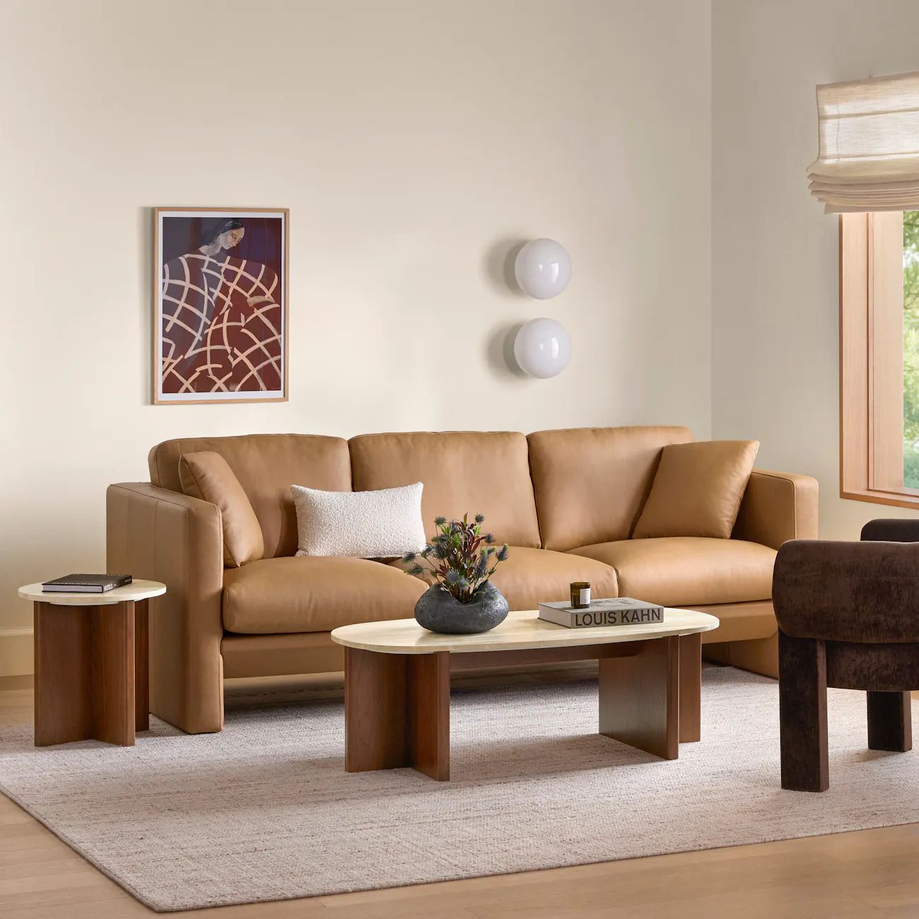 Travertine and walnut side table styled beside a leather sofa in a warm neutral living room