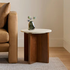 Travertine and walnut side table styled beside a leather sofa in a warm neutral living room