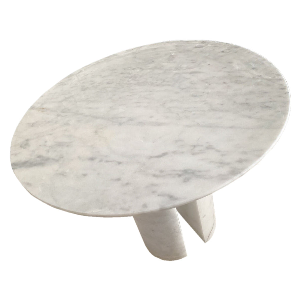 Close angled view of round marble tabletop and twin leg base showing natural veining