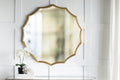 Gold sunburst mirror styled above a mirrored console table with brass lanterns