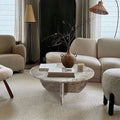 Round travertine coffee table styled in a neutral living room with a woven pendant light