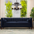 Luxury 84-inch sofa from the Cadence collection featuring a continuous tuxedo frame and shelter track arms in dark navy blue. Shown from a straight-on view in a styled residential space with a modern dark wood chandelier.