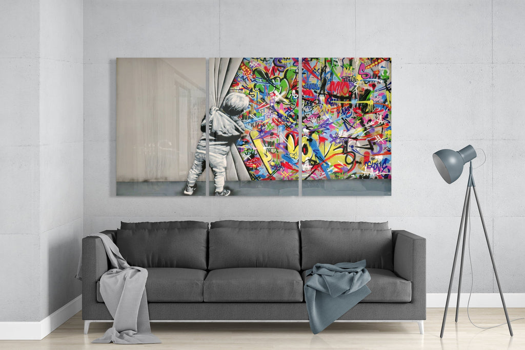 Glass triptych wall art displayed above a gray sofa in a modern living room