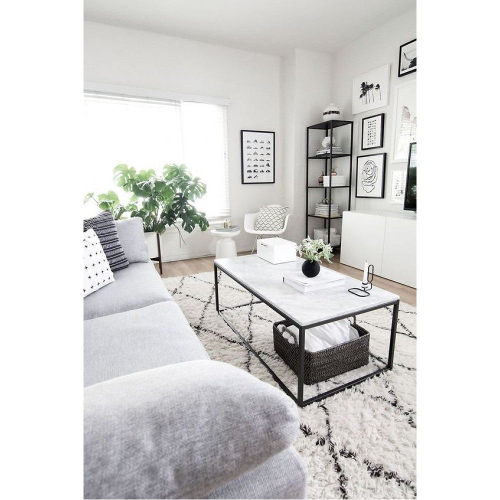 Marble coffee table with black frame and woven basket styled in a gray living room
