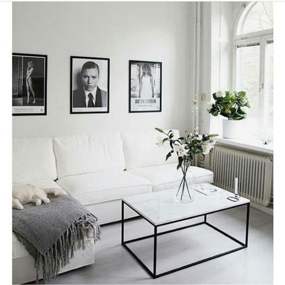 Marble coffee table with black metal legs in front of a white sectional sofa