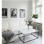 Marble coffee table with black metal legs in front of a white sectional sofa