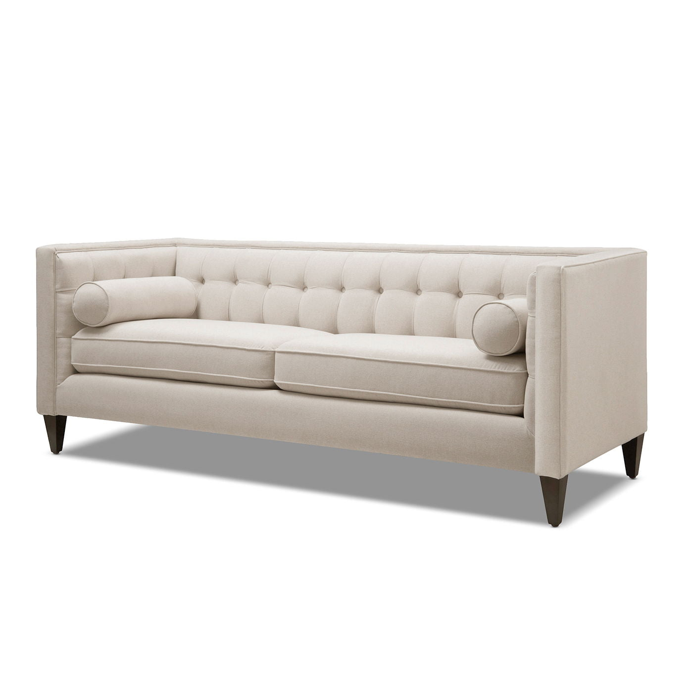 Minimalist 84-inch sofa from the Cadence collection featuring a crisp tuxedo silhouette and tapered accent legs in sky neutral beige. Shown from a three-quarter studio angle against a pure white background.