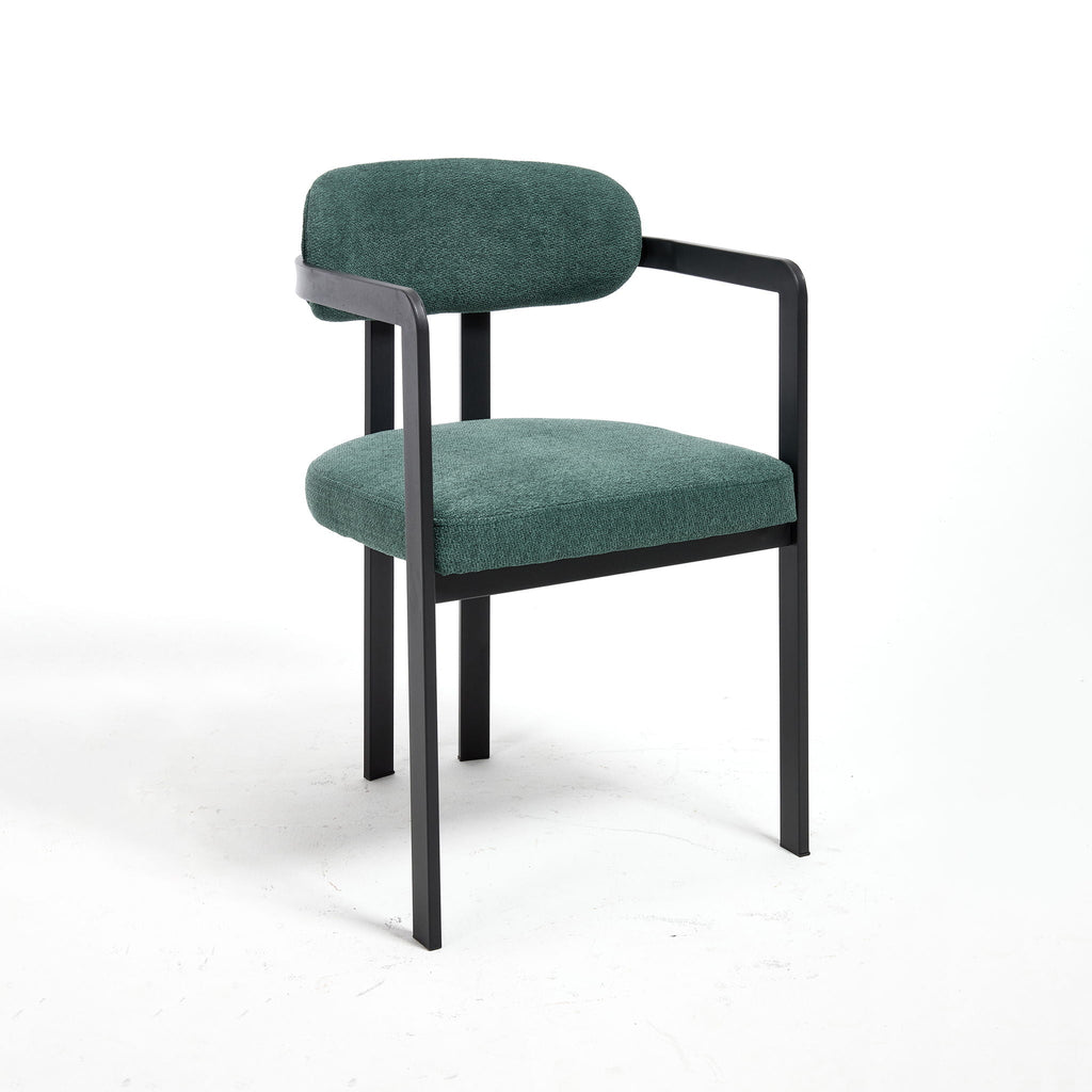 Minimalist three-quarter studio angle of the Helix dining chair, showcasing the tight antique green upholstery texture and the geometric matte black metal track arm assembly against a pure white background.