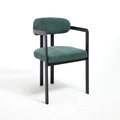Minimalist three-quarter studio angle of the Helix dining chair, showcasing the tight antique green upholstery texture and the geometric matte black metal track arm assembly against a pure white background.