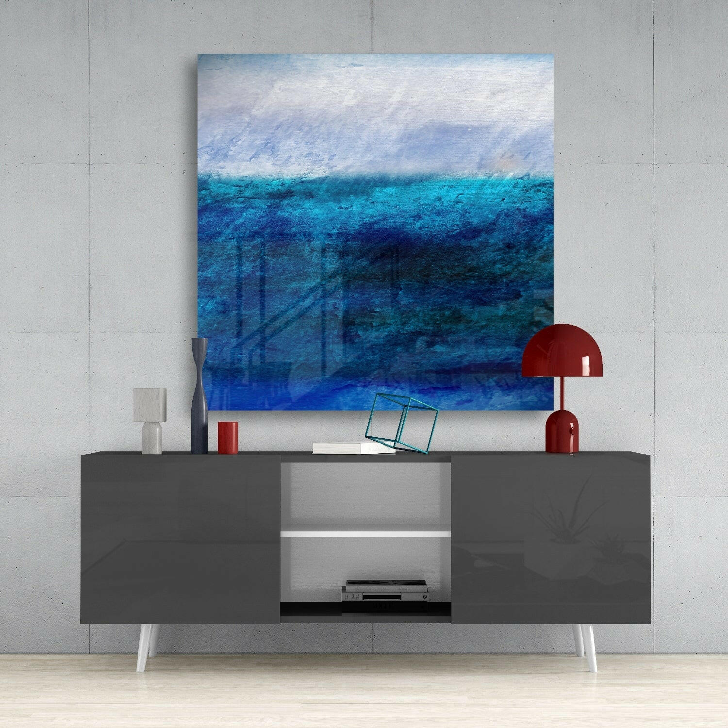 Large blue abstract glass wall art hanging above a gray credenza with a red lamp and decorative objects