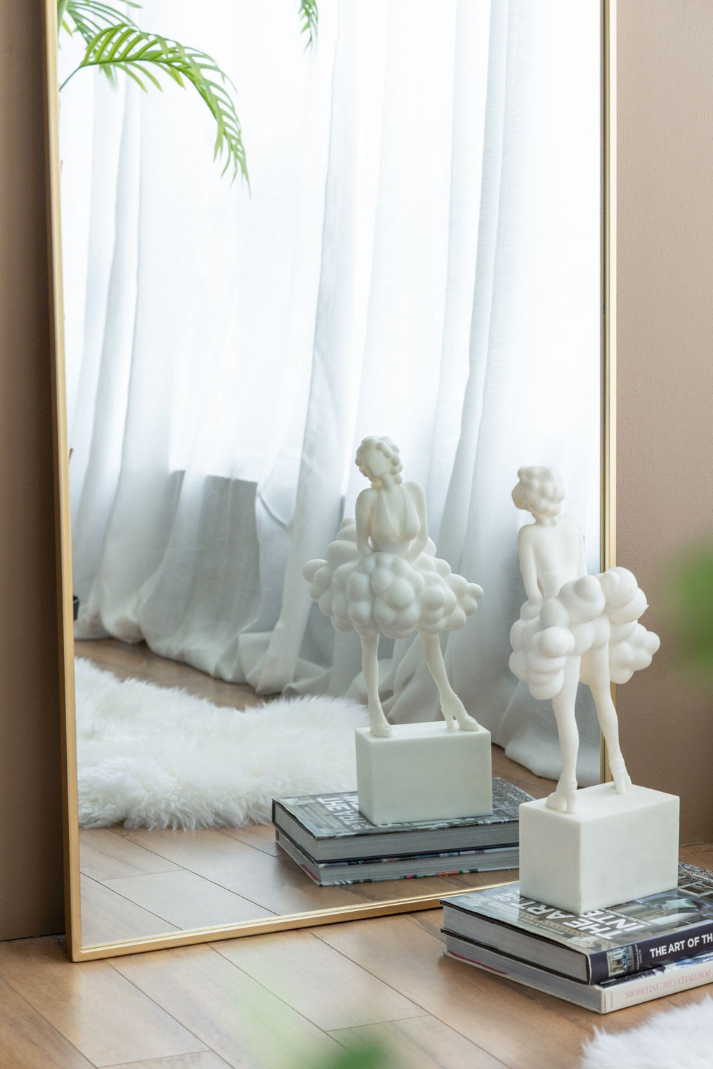 Close-up of the Ondine Mirror's gold arch frame reflecting a room with sculptural decor objects
