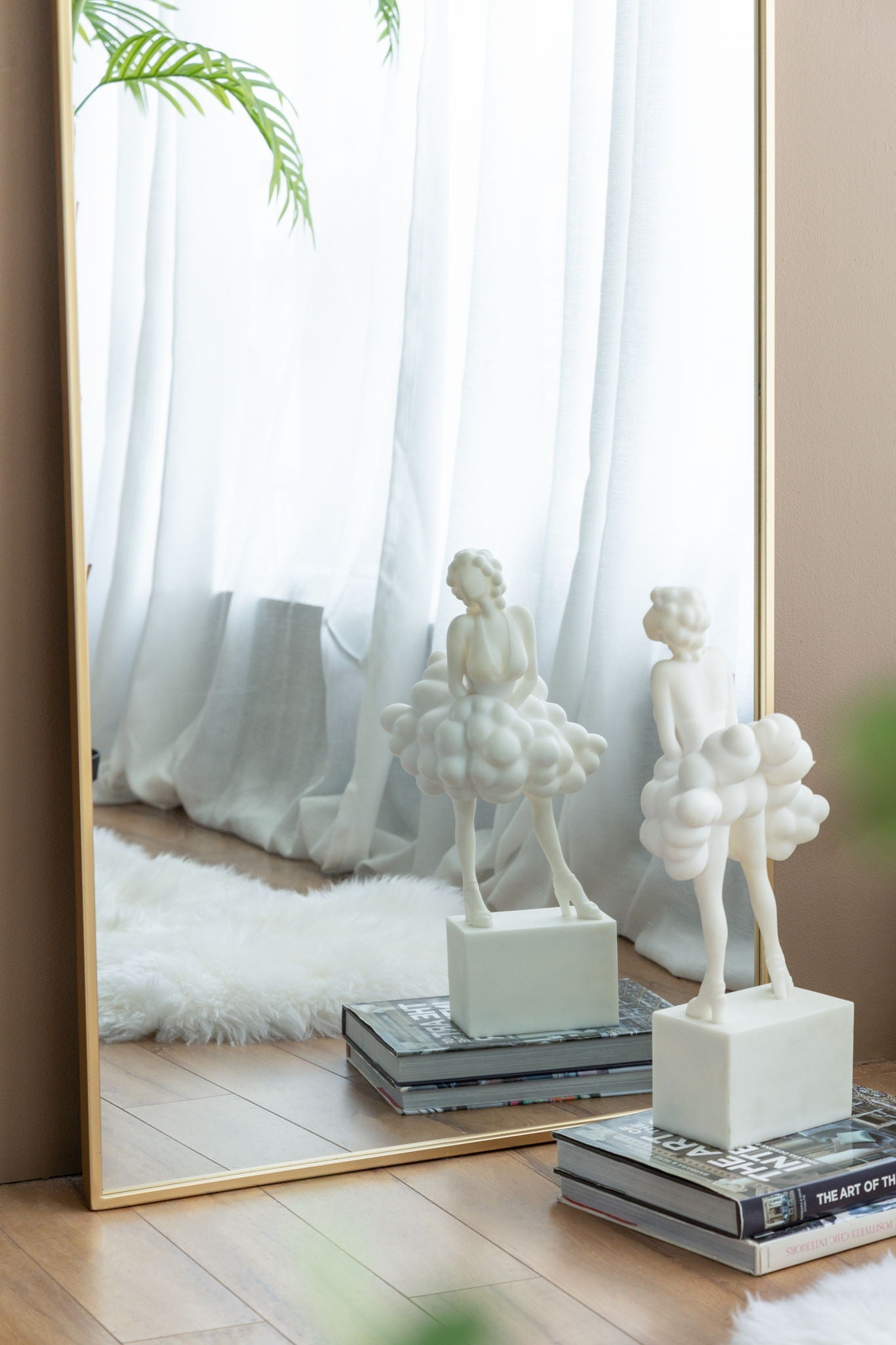 Close-up of the Ondine Mirror's gold arch frame reflecting a room with sculptural decor objects