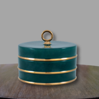 Peacock green and gold porcelain accent box displayed on a wood console against a neutral gray backdrop