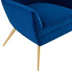 Close-up of the brushed gold splayed legs beneath the Renata Armchair's navy velvet frame