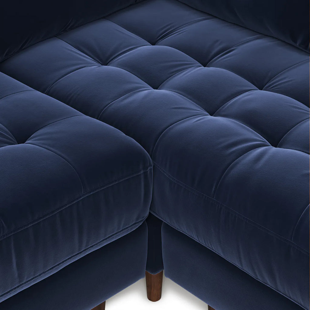 Overhead detail of diamond-tufted navy velvet bench seat and tapered wood leg on the Simone Sectional