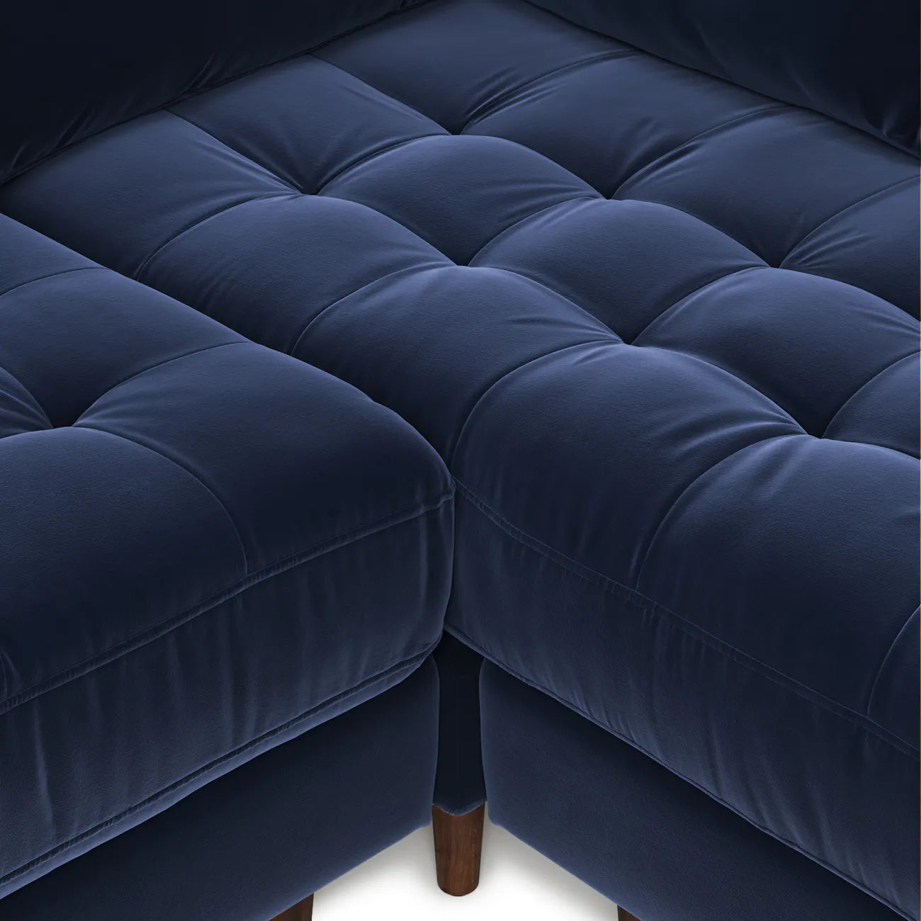 Overhead detail of diamond-tufted navy velvet bench seat and tapered wood leg on the Simone Sectional