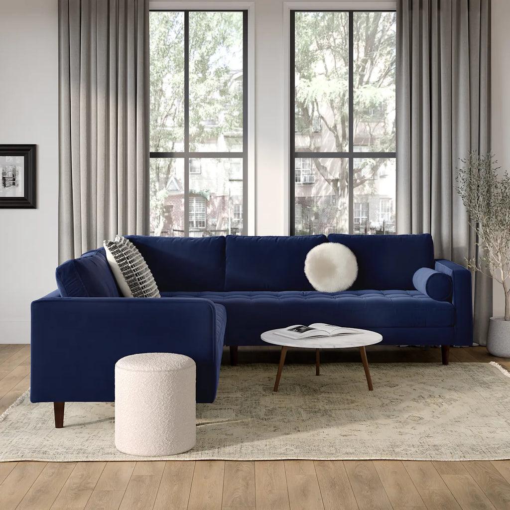 Navy velvet corner sectional styled in a living room with a marble coffee table and neutral rug