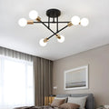 Black and gold sputnik-style chandelier hanging above a bed with gray bedding
