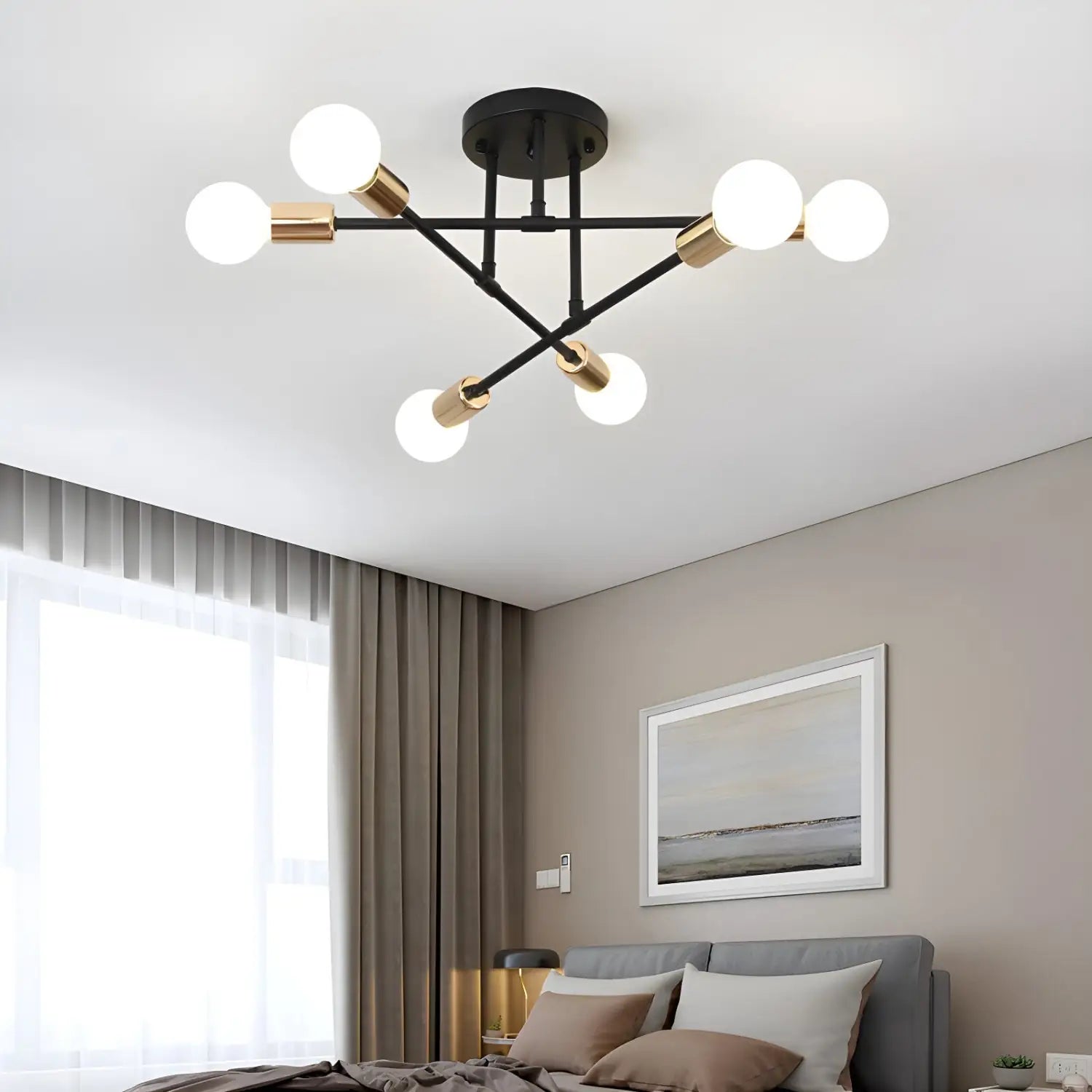 Black and gold sputnik-style chandelier hanging above a bed with gray bedding