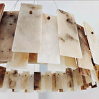 Close-up of overlapping alabaster stone panels showing natural veining and brass pin construction
