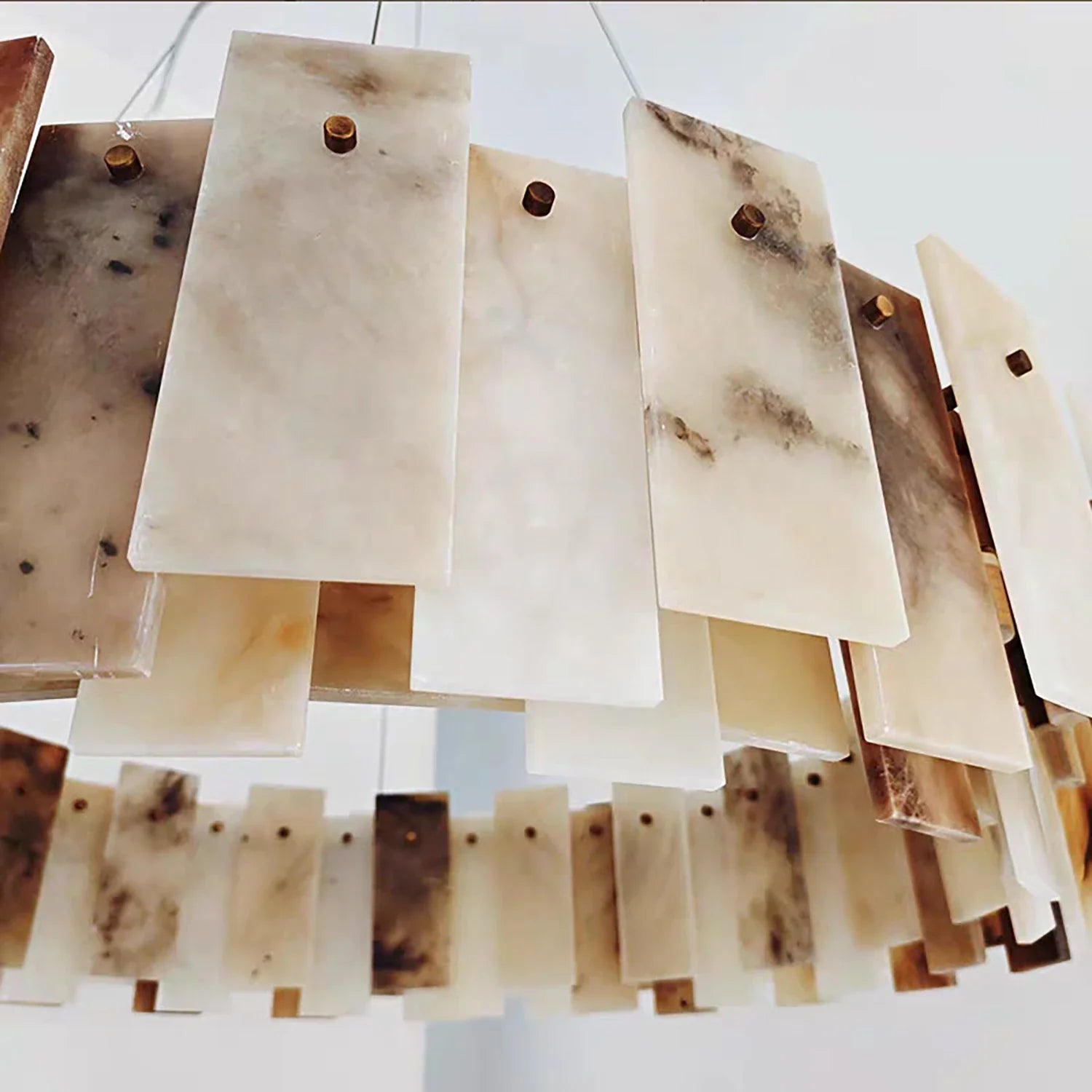 Close-up of overlapping alabaster stone panels showing natural veining and brass pin construction
