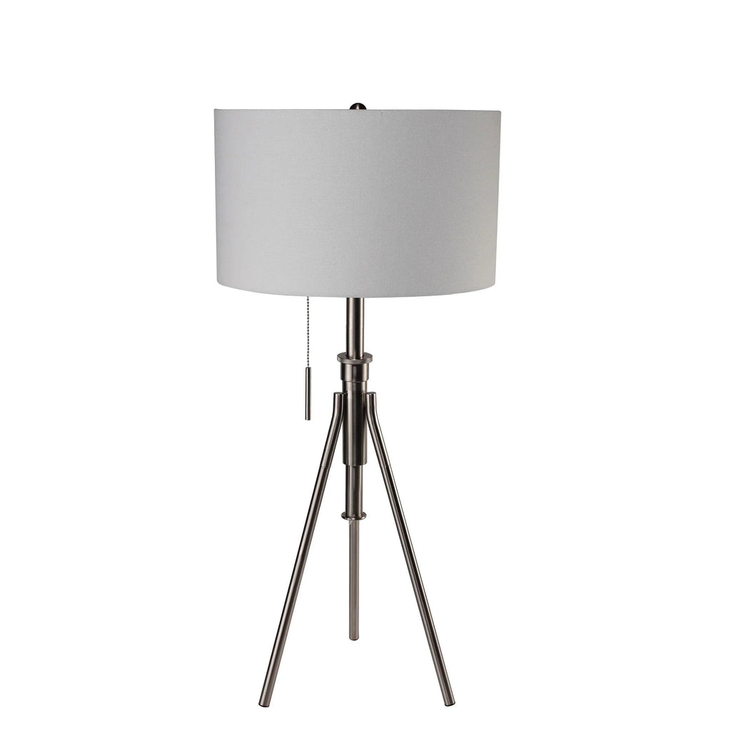 Brushed nickel tripod lamp with neutral fabric drum shade and pull chain on a white background