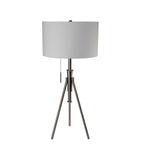Brushed nickel tripod lamp with neutral fabric drum shade and pull chain on a white background