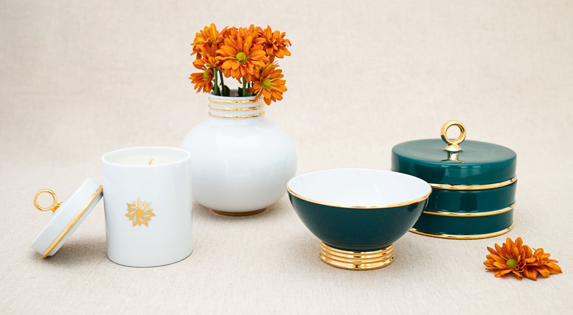 The peacock Arienne Box grouped with an ivory porcelain vase, candle, and matching bowl, styled with fresh orange flowers on a linen surface
