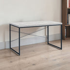 Weathered oak writing desk with iron X-brace frame styled against a neutral wall beside a wood bookshelf