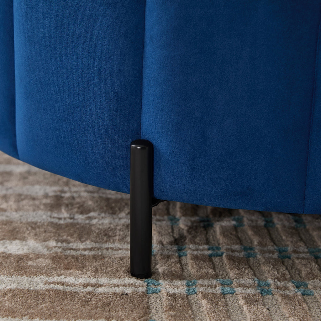 Macro close-up texture shot of the taut navy velvet channel tufting meeting a sleek, minimalist black metal leg.