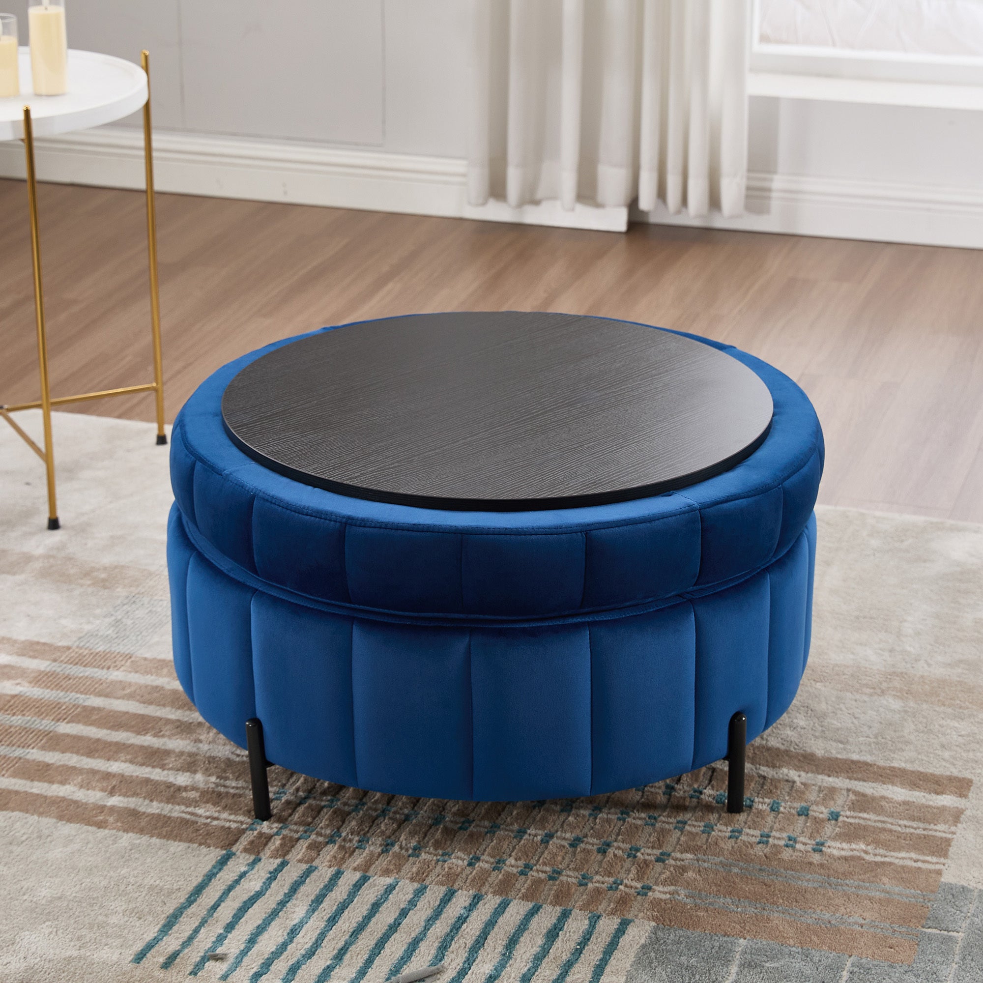 Studio vignette of the navy velvet storage ottoman with the lid inverted to showcase the built-in dark wood tray table surface.