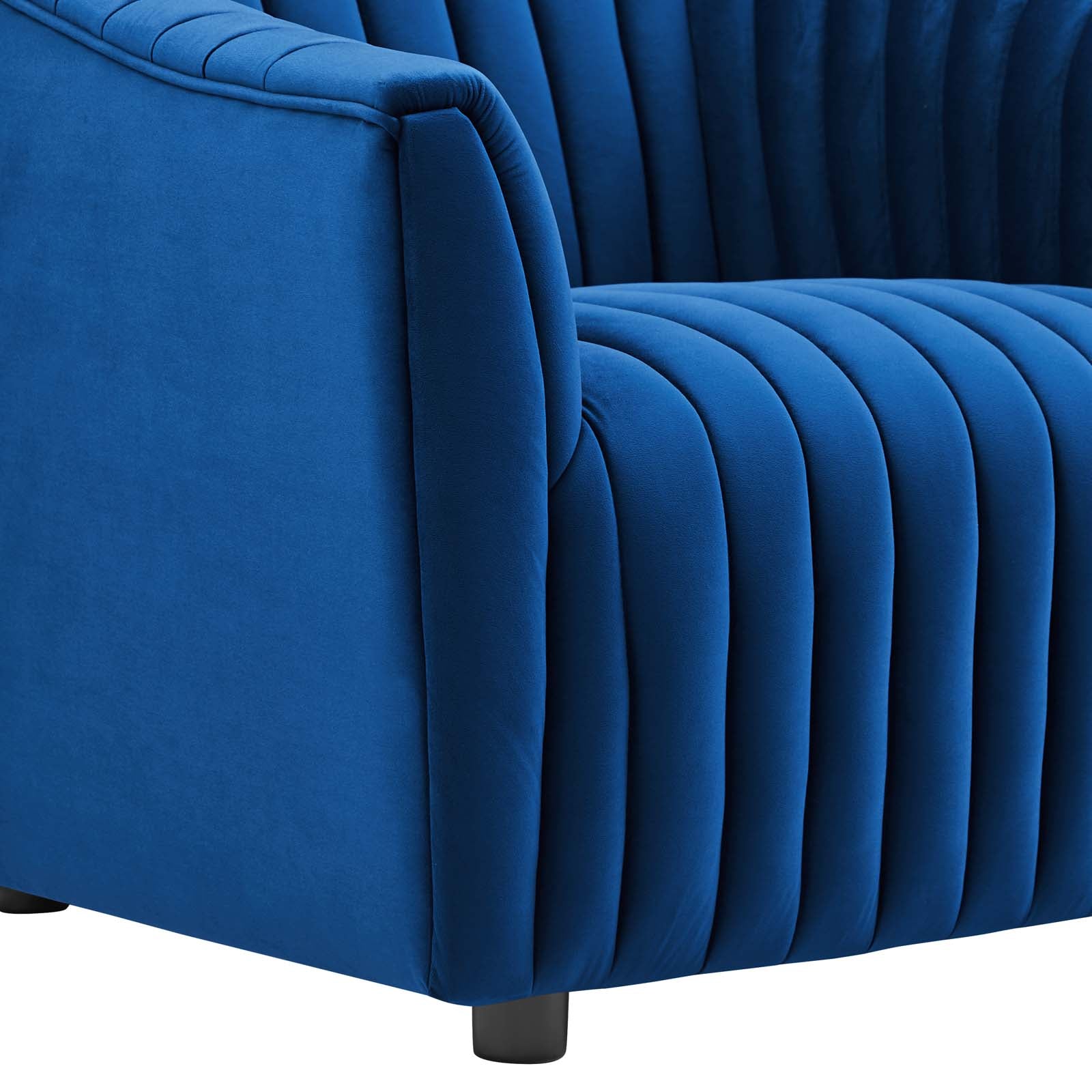 Detailed macro perspective of the crisp, taut vertical channel stitching running continuously down the armrest of the navy velvet armchair.