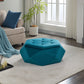Teal velvet faceted storage ottoman styled on a rug beside a beige armchair and potted plant
