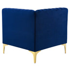 Rear view of the navy velvet corner chair showing continuous wraparound channel tufting and gold tapered legs