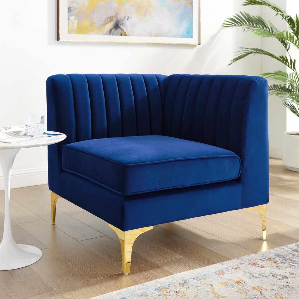 Navy velvet corner chair styled beside a marble side table and potted palm in a bright living room