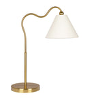 Brushed brass table lamp with curved arm and triangular white drum shade on a white background