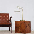 Brushed brass table lamp styled on a live-edge wood side table beside a woven leather chair