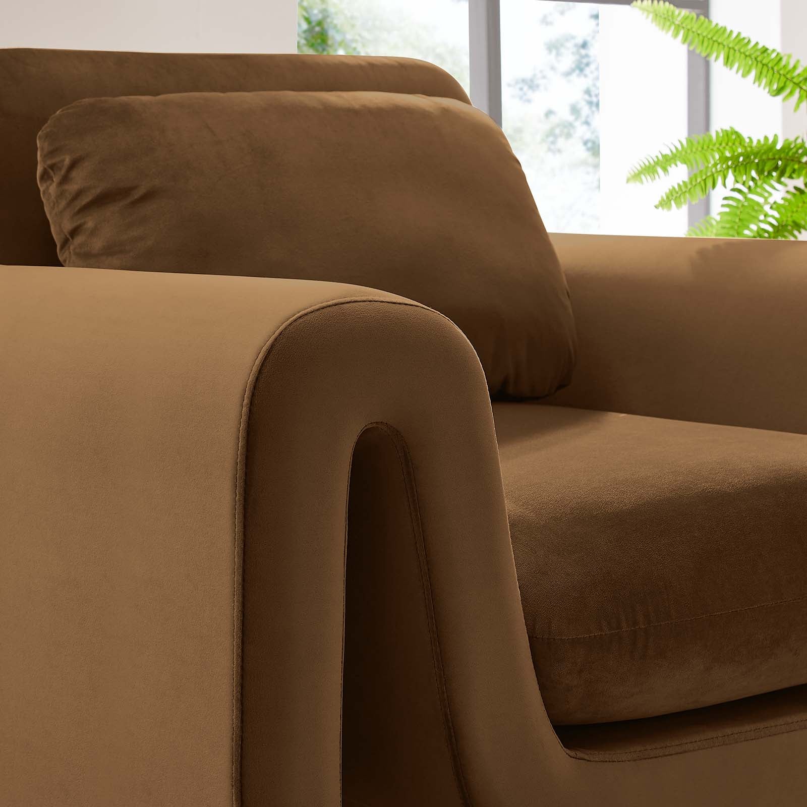 Title: The Odile Armchair | Full Sculptural Silhouette
Alt Text: Cognac velvet armchair with continuous curved arms on a white background