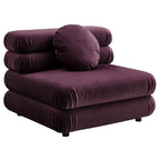 Deep plum velvet armless chair with stacked, rounded cushions and a round bolster pillow, shown against a white background